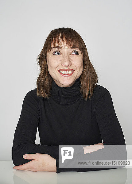 Porträt einer lächelnden jungen Frau in schwarzem Rollkragenpullover mit Blick nach oben