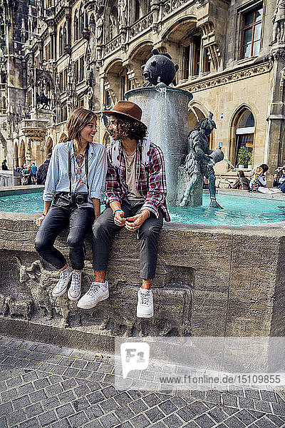 Young couple sitting at fountain