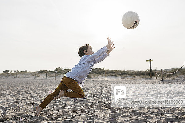Kleiner Junge spielt Fussball am Strand