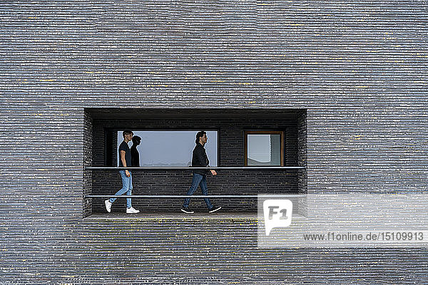 Zwei junge Männer gehen auf einem Balkon eines Gebäudes