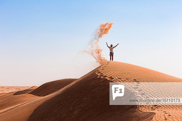 Sultanat Oman  Wahiba Sands  Mittelgroßer Mann spielt mit Sand in der Wüste
