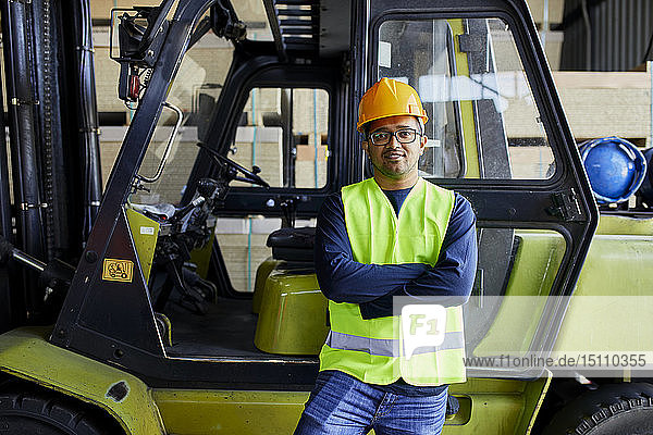 Portrait of confident worker at forklift in factory