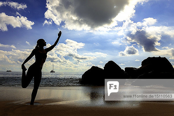 Seychellen  Mahe  Takamaka Beach  Silhouette einer Frau  die am Strand Yoga macht
