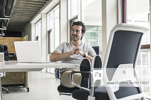 Junger Geschäftsmann arbeitet entspannt im modernen Büro  denkt