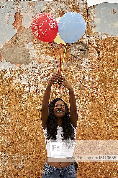 Porträt einer glücklichen jungen Frau mit drei Luftballons