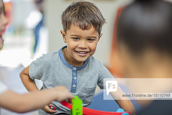 Glücklicher Junge spielt mit anderen Kindern im Kindergarten