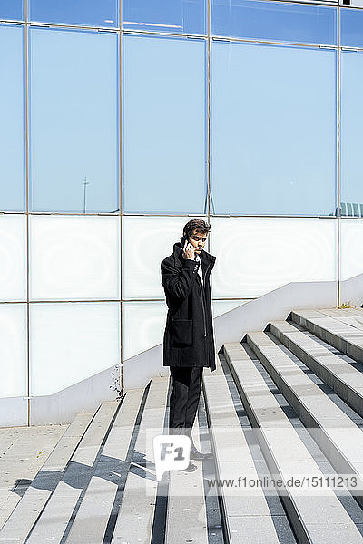 Businessman on cell phone on stairs in the city