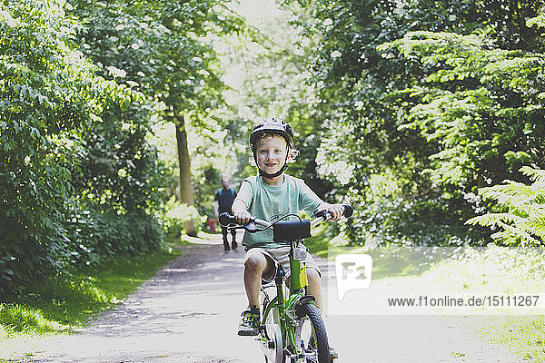 Portrait of proud little boy learning to ride bicycle