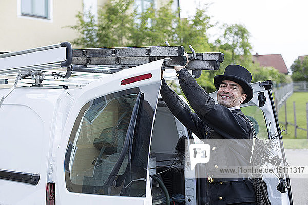Porträt eines lächelnden Schornsteinfegers bei seinem Lieferwagen