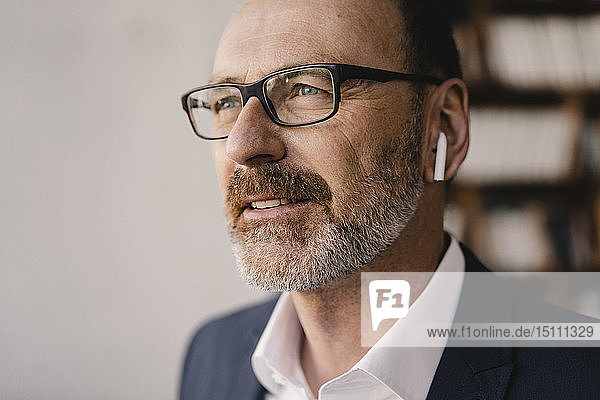 Porträt eines reifen Geschäftsmannes  der mit Bluetooth-Kopfhörern Musik hört