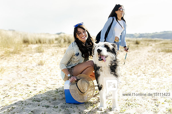 Zwei glückliche Frauen mit Hund am Strand