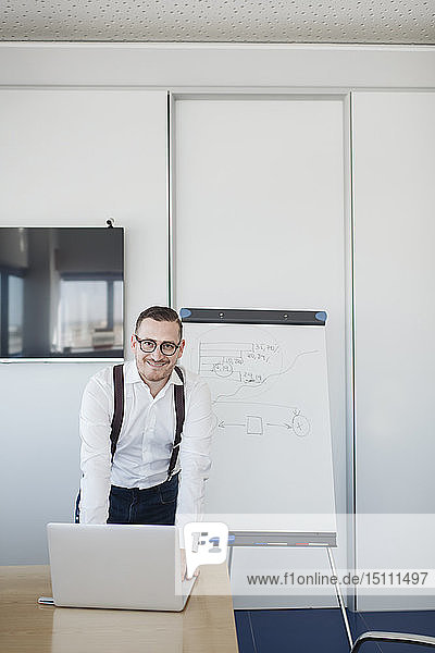 Porträt eines selbstbewussten Geschäftsmannes mit Laptop im Konferenzraum im Büro
