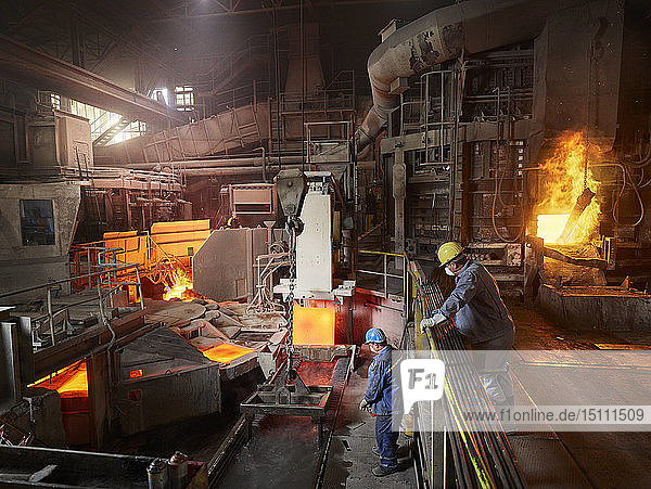 Industry Worker lifting copper plates with indoor crane for cooling in water basin