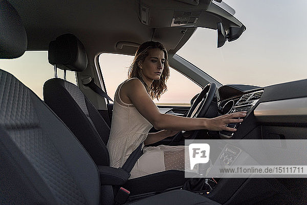 Blond woman driver choosing a radio channel in her car