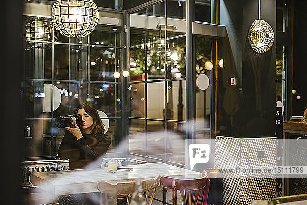 Junge Frau fotografiert nachts in einer Bar mit einer Kamera