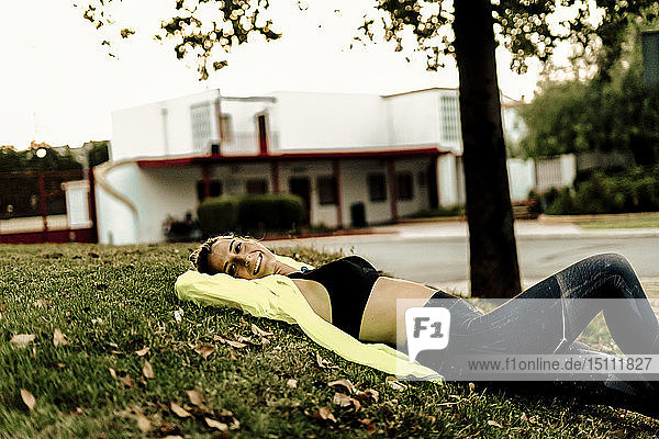 Sporty woman relaxing on grass after workout