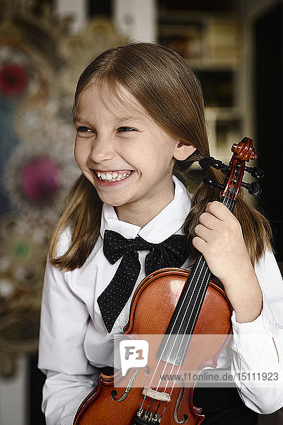 Portrait of a happy girl with a violin at home