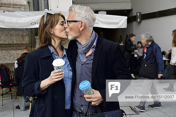 Mature couple with reusable bamboo cups kissing in the city