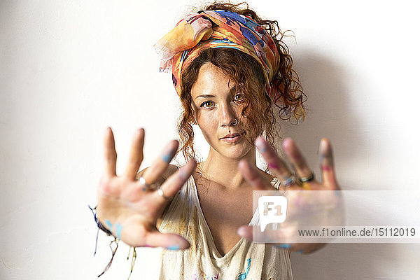 Porträt einer jungen Künstlerin in ihrem Atelier mit ihren gemalten Händen