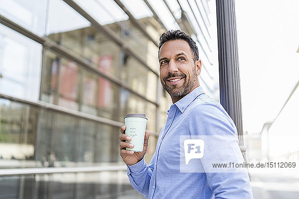 Porträt eines lächelnden Geschäftsmannes mit Kaffee zum Mitnehmen in der Stadt