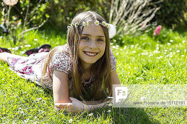 Porträt eines glücklichen Mädchens  das auf einer Wiese im Garten liegt