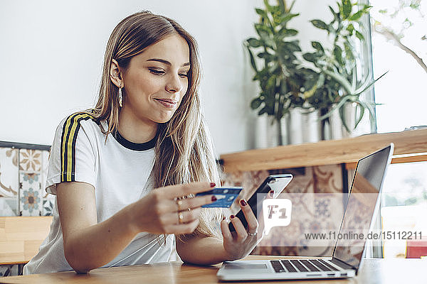 Junge Frau mit Kreditkarte und Laptop