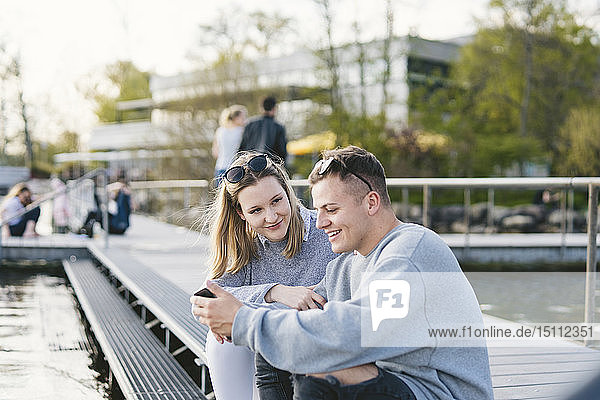 Junges Paar sitzt auf einem Steg am Zürichsee  Zürich  Schweiz