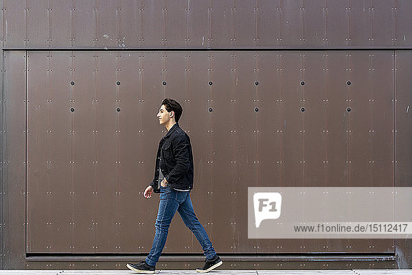 Young man walking along a wall