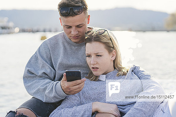 Young couple on jetty at Lake Zurich looking at cell phone  Zurich  Switzerland