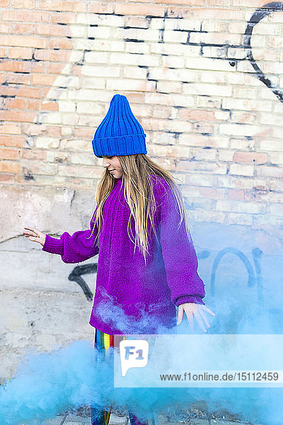 Junges Mädchen mit türkisfarbenem Farbpuder im Hintergrund