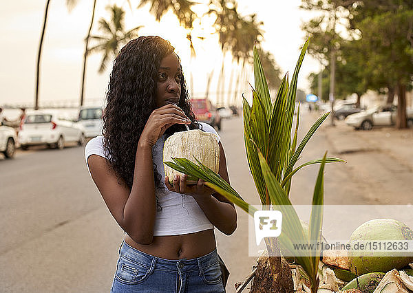 Mocambique  Maputo  Porträt einer jungen Frau  die auf der Strasse Kokosnusswasser trinkt