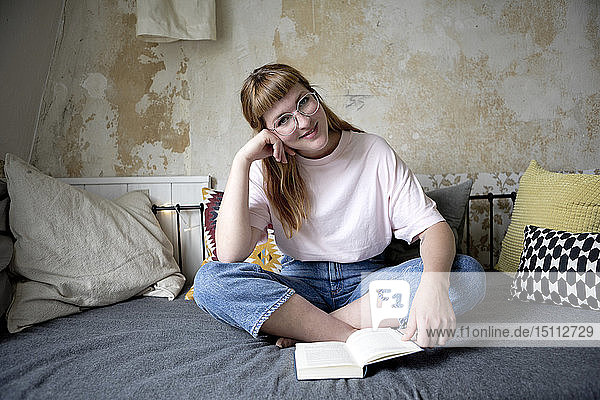 Studentin liest in ihrem Zimmer ein Buch