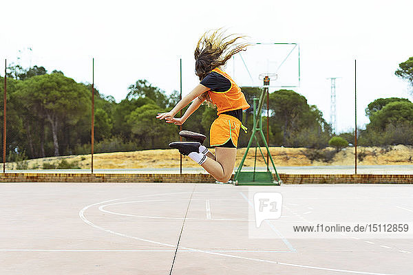 Teenager-Mädchen springt auf Basketballplatz