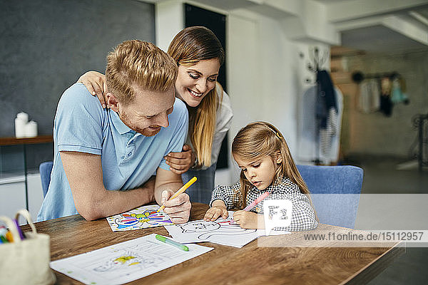 Mother and father watching daughter  painting coloring book