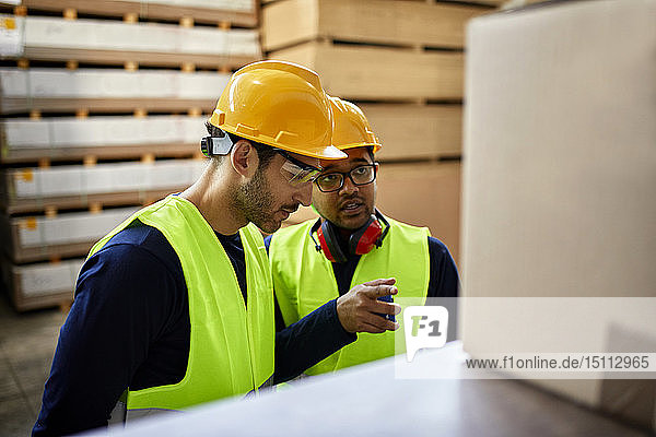 Two workers talking in factory warehouse