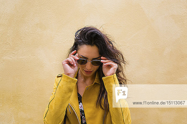 Porträt einer jungen Frau mit gelber Lederjacke und Sonnenbrille