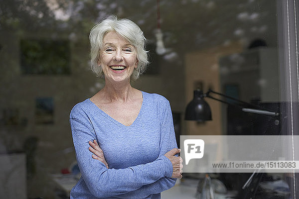 Portrait of happy mature woman in her office looking out of window
