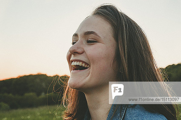 Porträt eines lachenden Teenager-Mädchens in der Natur bei Sonnenuntergang
