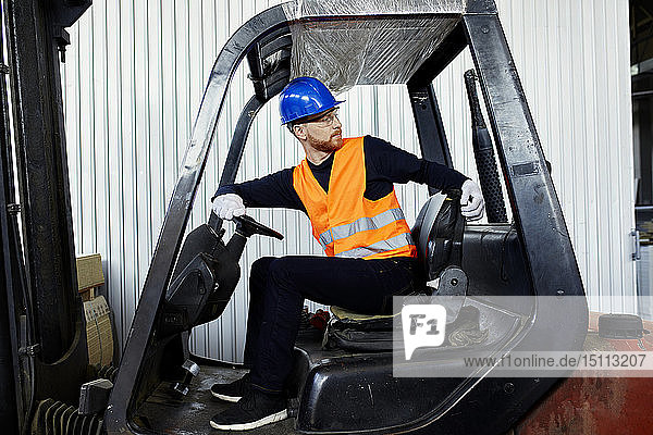 Worker on forklift in factory turning round