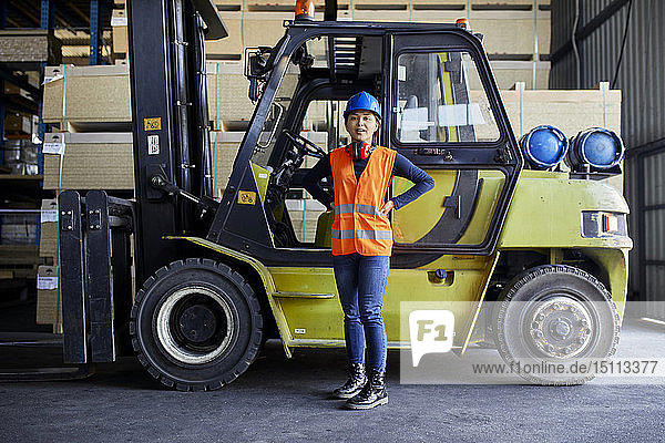 Portrait of confident female worker at forklift in factory