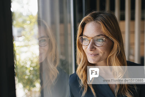 Porträt einer lächelnden Geschäftsfrau  die aus dem Fenster schaut