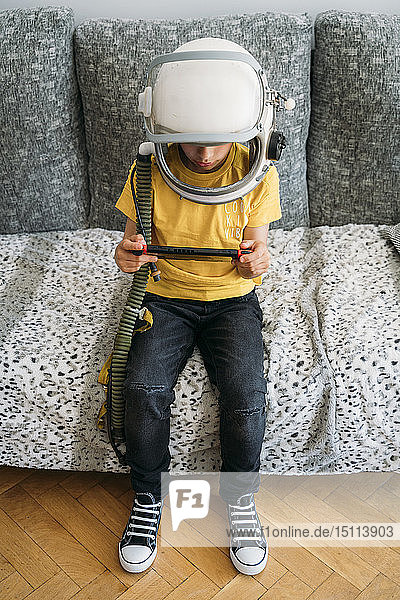 Junge  der ein Videospiel auf einer Spielkonsole spielt und einen Weltraumhut trägt