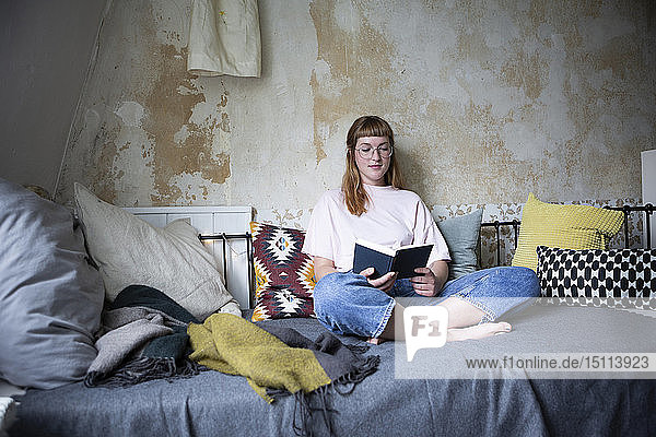 Female student reading a book in her room