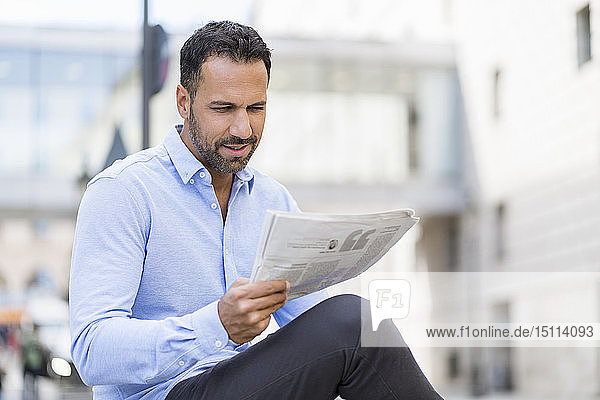 Geschäftsmann liest Zeitung in der Stadt