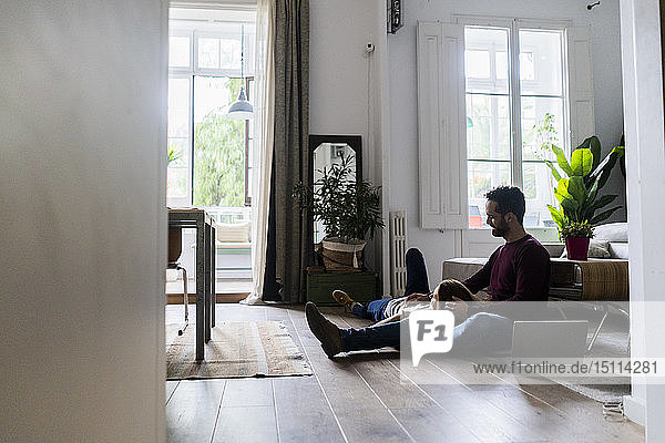 Affectionate couple with laptop relaxing on the floor at home