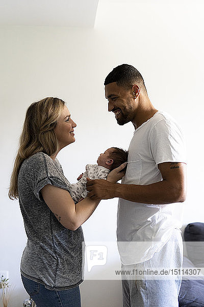 Happy parents holding newborn baby at home