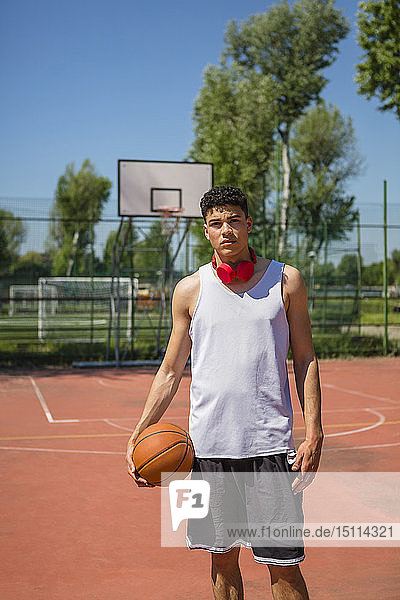 Junger Mann hält Basketball  rote Kopfhörer
