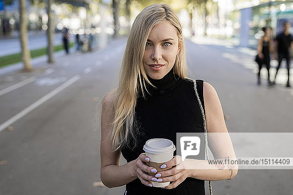 Porträt einer lächelnden blonden Frau mit Kaffee zum Mitnehmen