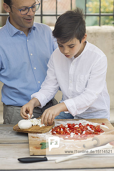 Vater und Sohn bereiten gemeinsam Pizza zu