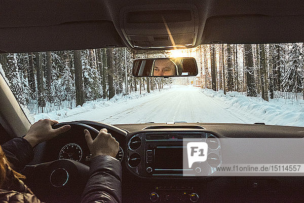 Finnland  Kuopio  Frau fährt Auto in Winterlandschaft bei Sonnenuntergang